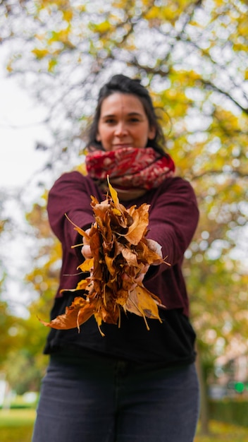 Lächelnde Frau, die eine Handvoll Herbstblätter hält