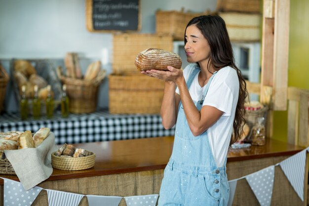 Lächelnde Frau, die einen runden Brotlaib an der Theke riecht