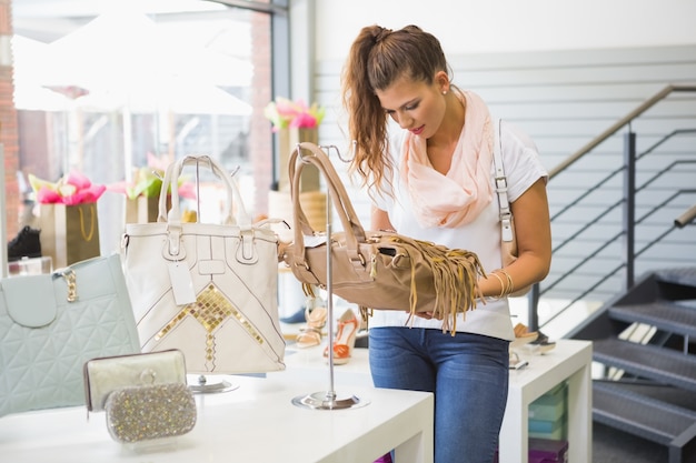 Lächelnde Frau, die Handtasche betrachtet