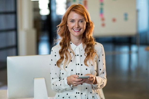 lächelnde Frau, die Handy im Büro hält