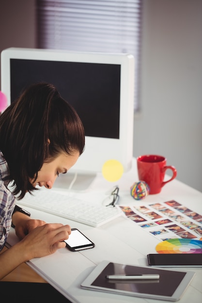 Lächelnde Frau, die Handy im Büro verwendet