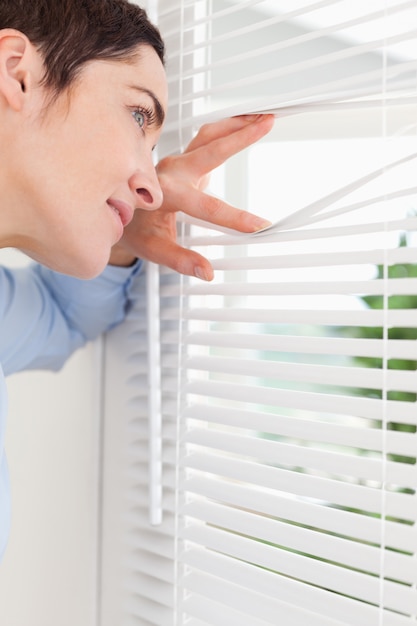 Lächelnde Frau, die heraus ein Fenster späht