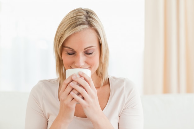 Lächelnde Frau, die ihren Tasse Kaffee riecht