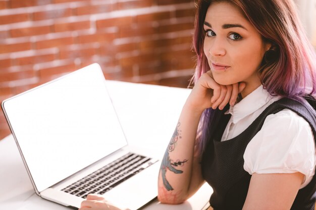 Lächelnde Frau, die mit Laptop im Büro sitzt