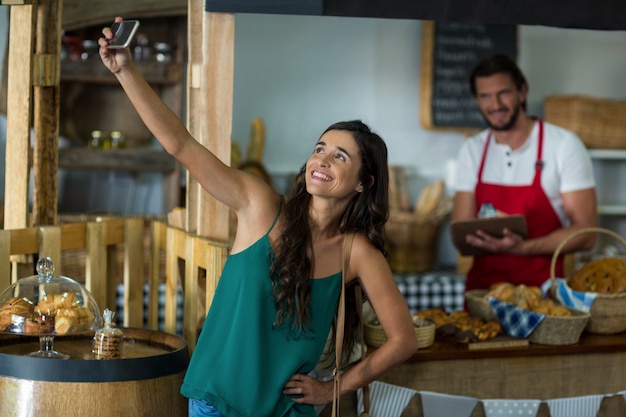 Lächelnde Frau, die selfie mit Handy am Schalter spricht