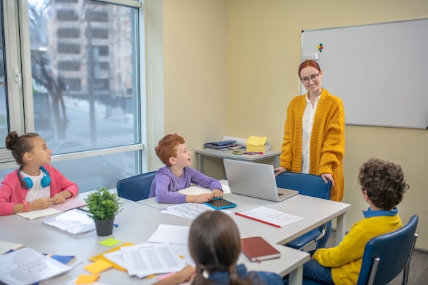 Lächelnde Frau, die vor den Schulkindern steht