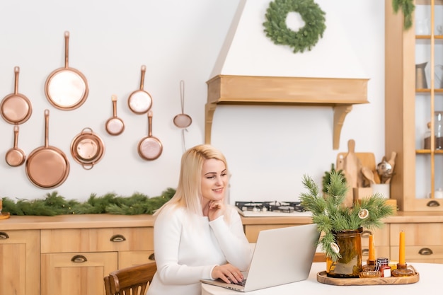 Lächelnde Frau, die zu Hause auf einem Laptop-Computer im Internet surft,