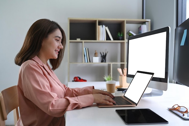 Lächelnde Frau, die zu Hause mit mehreren Geräten arbeitet