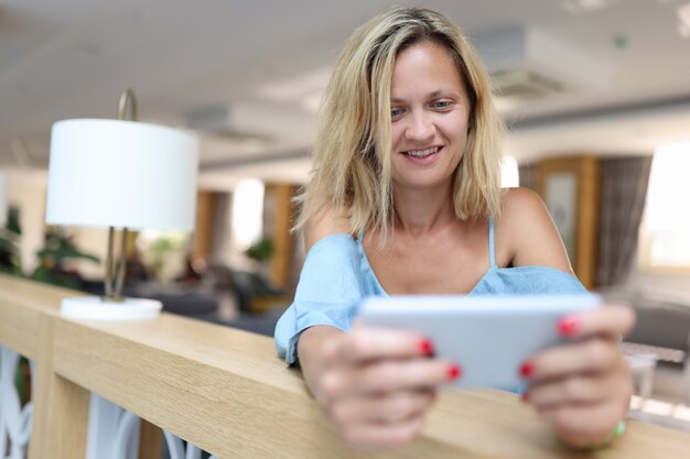 Lächelnde Frau hält Smartphone und schaut auf Bildschirmkorrespondenz und Mail-Viewing-Konzept