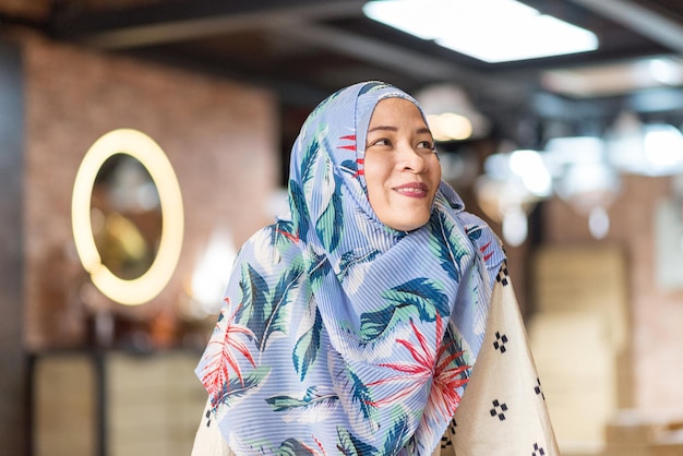 Foto lächelnde frau im hijab, die in ein café schaut