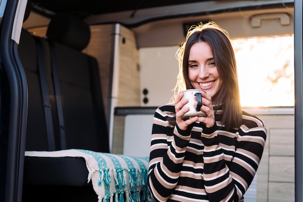 Lächelnde Frau in einem Wohnmobil mit einer Tasse in der Hand