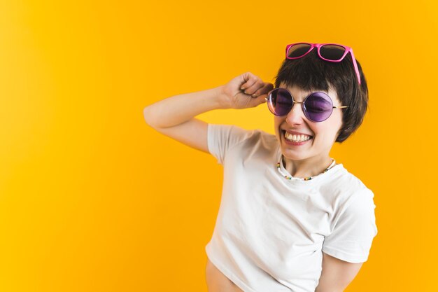 Lächelnde Frau in zwei Sonnenbrillen leuchtend orange Hintergrund Glückskonzept