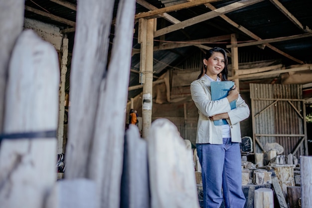 Foto lächelnde frau, inhaberin eines steinhandwerksunternehmens, hält klemmbrett in der steinhandwerkswerkstatt