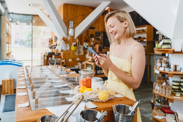 Lächelnde Frau kauft Produkte im Laden mit dem Smartphone