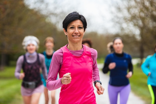 Foto lächelnde frau leitet eine gruppe läuferinnen beim training in der natur konzept der körperlichen fitness auch im alter