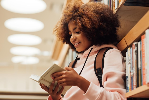 Lächelnde Frau liest ein Buch in der Bibliothek