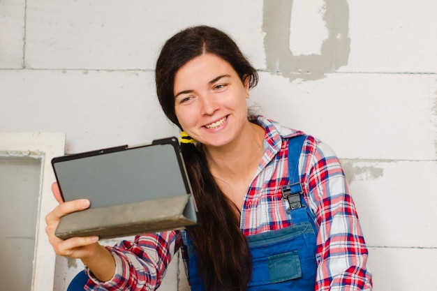 Lächelnde Frau macht Reparaturen in der alten Wohnung selbst und kommuniziert auf dem Tablet