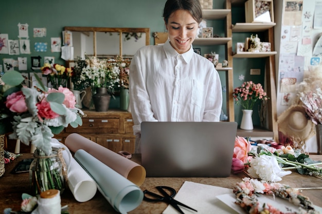 Lächelnde Frau mit einem Laptop im Blumenladen