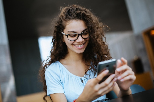 Foto lächelnde frau mit handy am tisch