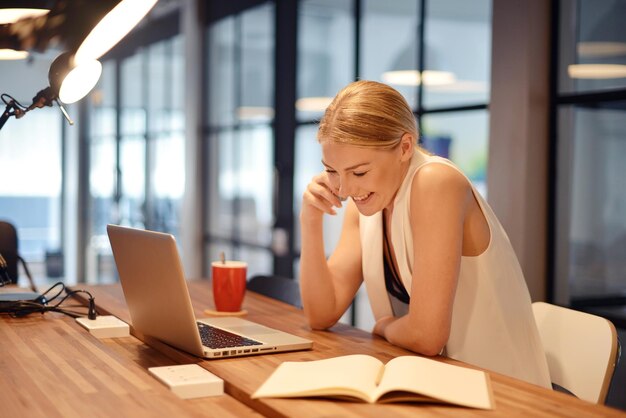 Lächelnde Frau mit Laptop auf dem Tisch im Büro