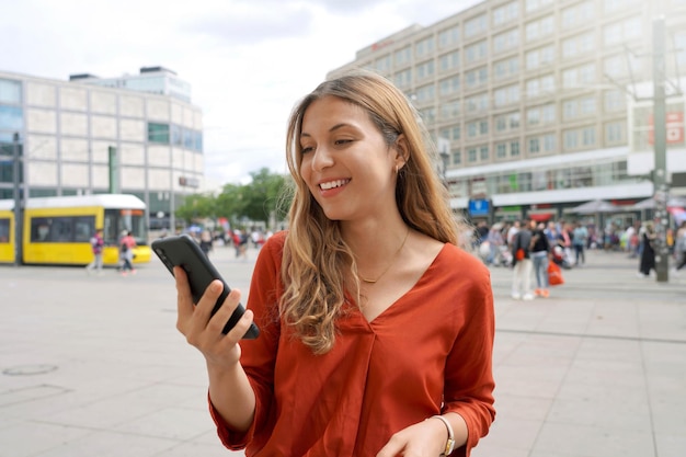 Lächelnde Frau mit Smartphone auf dem Alexanderplatz in Berlin Deutschland