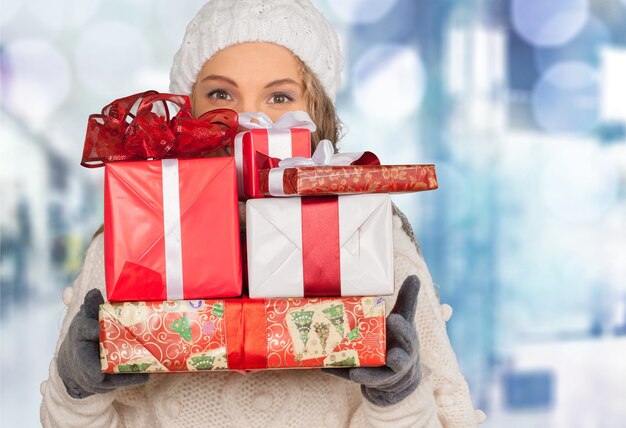 Lächelnde Frau mit vielen Geschenkboxen im Hintergrund