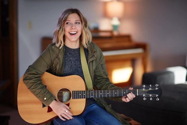 Lächelnde Frau spielt zu Hause Gitarre