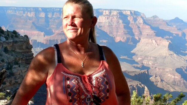 Foto lächelnde frau steht auf dem berg gegen den himmel