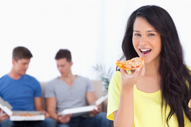 Lächelnde Frau ungefähr, zum einiger Pizza mit ihren Freunden im Hintergrund zu essen