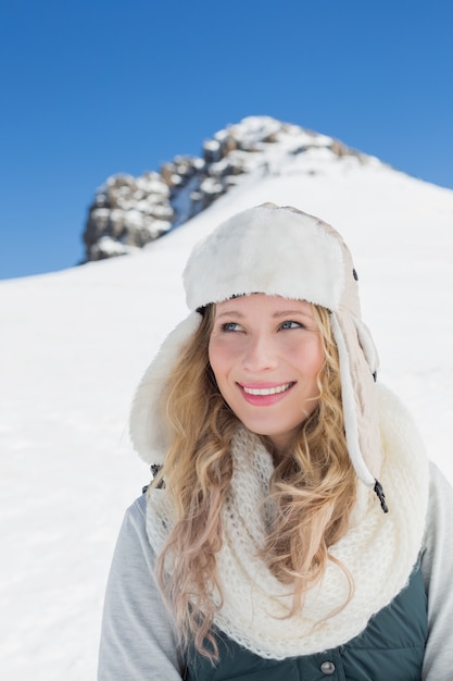 Lächelnde Frau vor geschneitem Hügel und blauem Himmel des freien Raumes