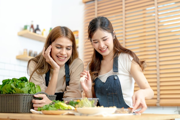 Lächelnde Frauen bereiten frisches, gesundes Salatgemüse zu. Frau sitzt in der Speisekammer in einer schönen Innenküche. Die saubere Diätkost aus lokalen Produkten und Zutaten. Marktfrisch