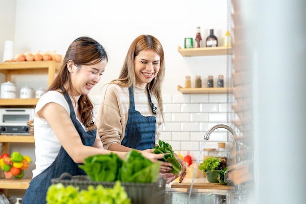 Lächelnde Frauen bereiten frisches, gesundes Salatgemüse zu. Frau steht in der Speisekammer in einer schönen Innenküche. Die saubere Diätnahrung aus lokalen Produkten und Zutaten. Marktfrisch