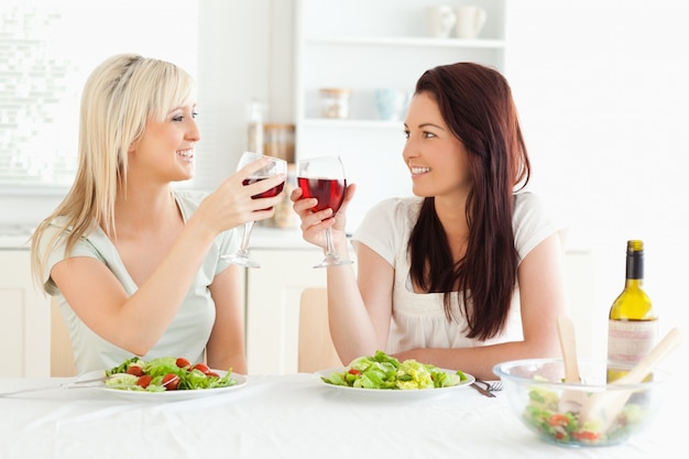 Lächelnde Frauen, die mit Wein rösten