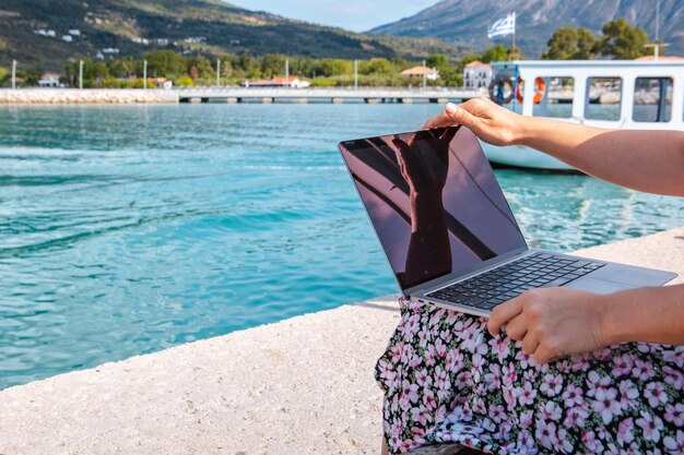 Lächelnde Freiberuflerin, die im Freien am Stadthafen Kopienraum am Laptop arbeitet