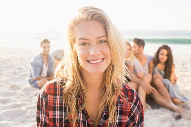 Lächelnde Freunde, die auf Sand sitzen