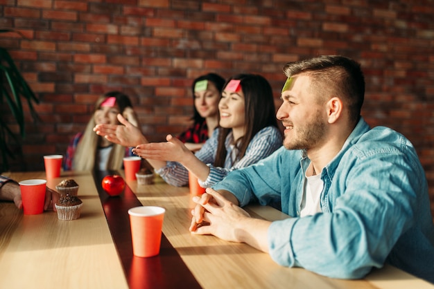 Lächelnde Freunde, die Aufklebernotizen zur Stirn spielen