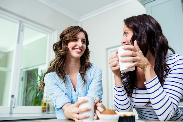 Lächelnde Freunde, die bei Tisch Kaffeetassen halten