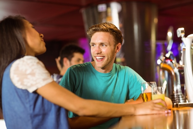 Lächelnde Freunde, die Bier und Mischgetränk sprechen und trinken