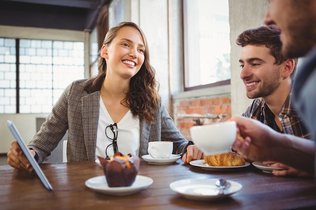 Lächelnde Freunde, die Kaffee genießen und an der Tablette verwenden