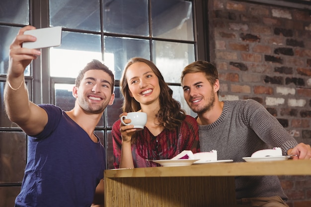 Lächelnde Freunde, die Kaffee trinken und selfies nehmen