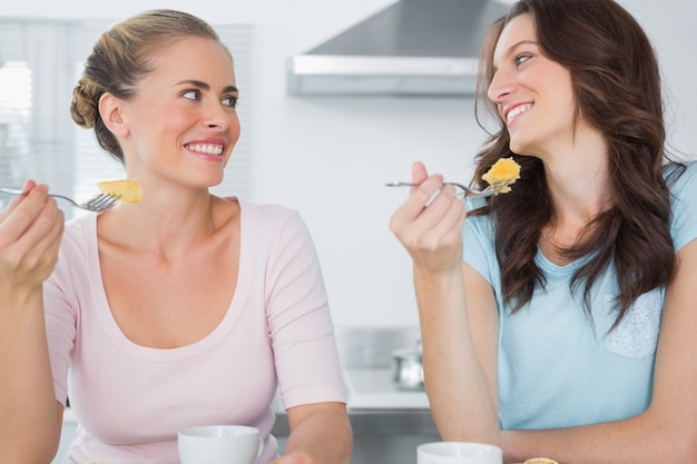 Lächelnde Freunde, die Kuchen essen und Kaffee trinken