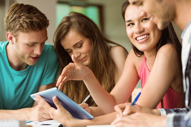 Foto lächelnde freunde, die unter verwendung des tabletten-pc für teamwork sitzen