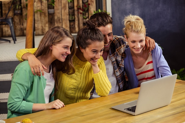 Foto lächelnde freunde, die zusammen laptop verwenden