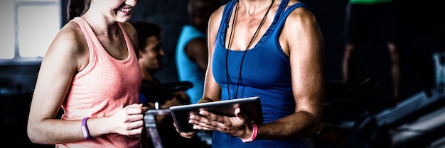 Lächelnde Freunde mit digitalem Tablet im Fitnessstudio