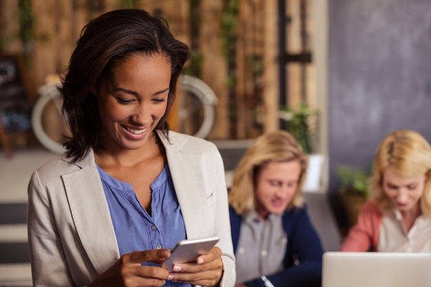 Lächelnde Geschäftsfrau, die einen Smartphone verwendet