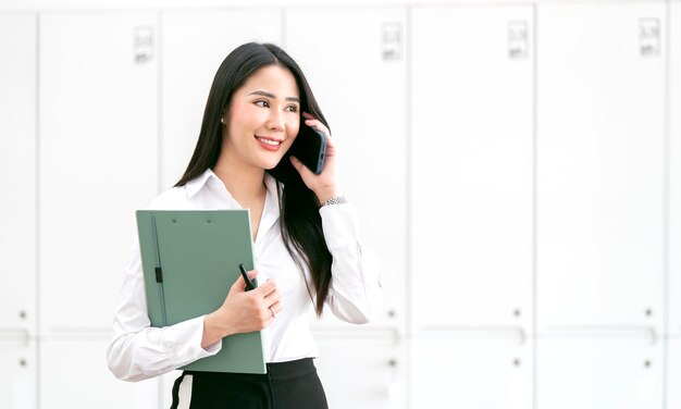 Lächelnde Geschäftsfrau, die ihr Telefon im Büro benutzt