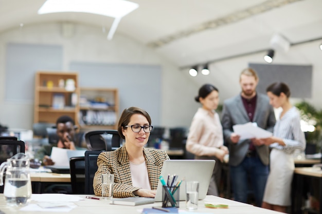 Lächelnde Geschäftsfrau, die im Open Space Office arbeitet