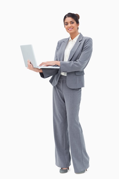 Lächelnde Geschäftsfrau, die Laptop bei der Stellung verwendet