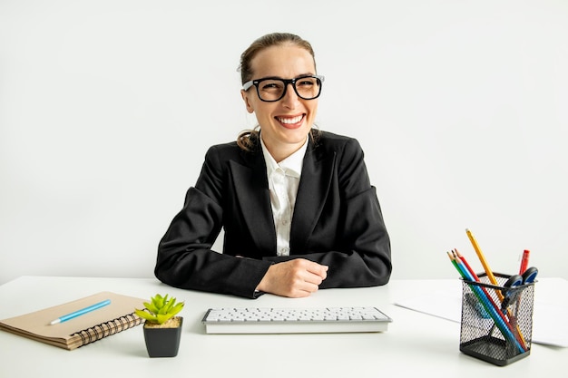 Lächelnde Geschäftsfrau mit Brille und Tastatur am Arbeitsplatz