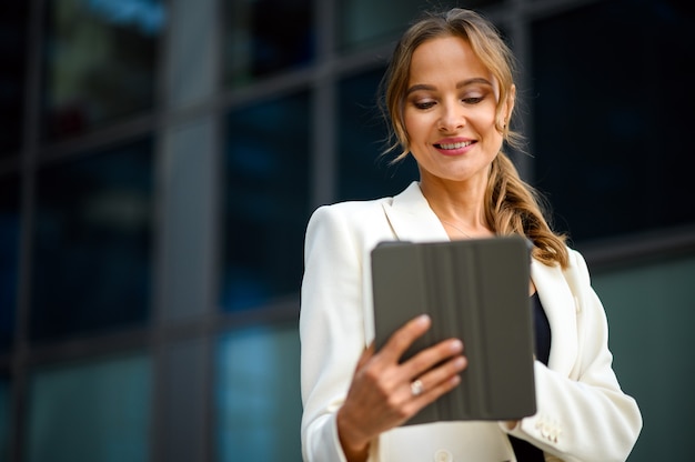 Lächelnde Geschäftsfrau mit einem digitalen Tablet im Freien